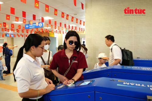 Nhân viên ga tức trực hướng dẫn hành khách sử dụng hệ thống soát vé tự động.