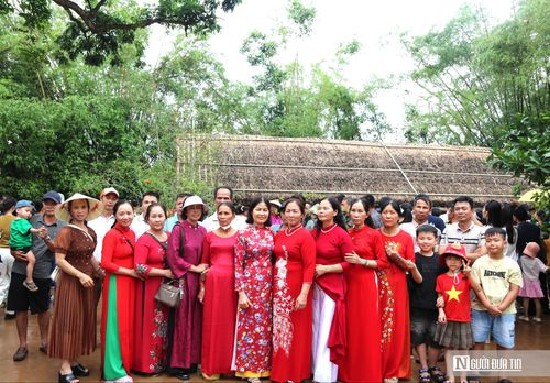 Các đoàn du khách chụp ảnh lưu niệm bên mái nhà tranh ở quê nội Bác Hồ.
