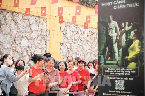 Du khách chụp ảnh lưu niệm trong lúc xếp hàng chờ đến lượt vào tham quan di tích Nhà tù Hỏa Lò. Ảnh: Phạm Tuấn Anh - TTXVN