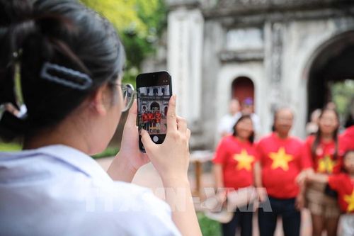 Du khách chụp ảnh kỷ niệm khi đến tham quan Văn Miếu - Quốc Tử Giám. Ảnh: Phạm Tuấn Anh - TTXVN