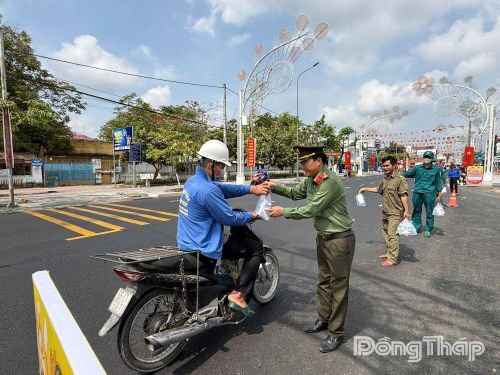 Chiến sĩ Công an xã Phú Hựu ân cần trao quà cho người đi đường