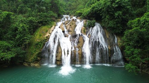 Tại đây, nước từ dòng suối trên cao liên tục chảy về tỏa ra đổ xuống vách đá cao chừng hơn 10m vẽ nên bức tranh thơ mộng giữa núi rừng. Ngay dưới vách đá này, một hồ nước trong xanh rộng chừng 5.000m2 tạo nên khung cảnh tuyệt đẹp.