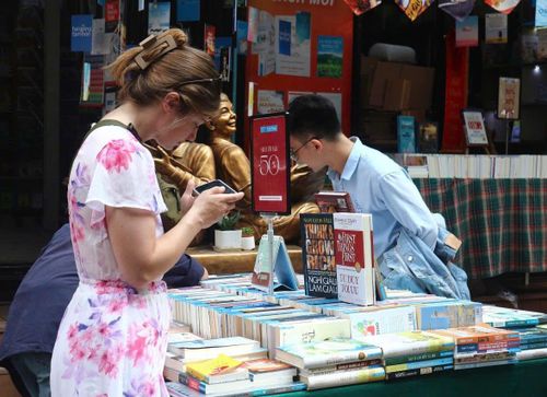 Du khách nước ngoài tìm hiểu sách tại các gian hàng giảm giá, khuyến mãi.