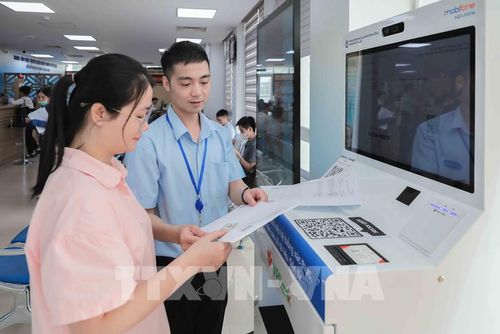 Cán bộ Chi nhánh số 6 Trung tâm Phục vụ hành chính công Hà Nội tại xã Gia Lâm hướng dẫn người dân dùng Ki ốt AI cấp bản sao số điện tử miễn phí, dùng trọn đời. Hệ thống giúp thao tác một lần, kết quả tự động tích hợp vào ví iHanoi mà không cần gặp trực tiếp cán bộ chuyên trách. Ảnh: Phan Phương – TTXVN