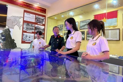 Cựu chiến binh Nguyễn Tiến Quynh hướng dẫn sinh viên tìm hiểu hiện vật, hình ảnh tư liệu tại Bảo tàng Thanh Hóa.