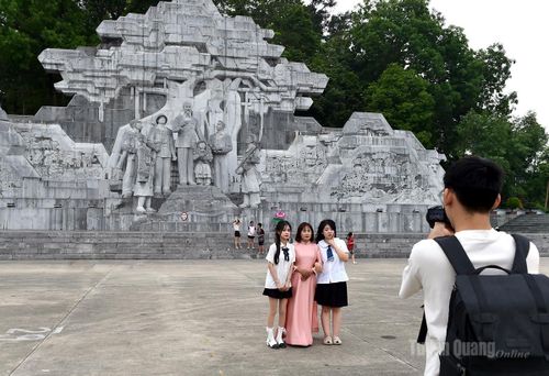 Khách du lịch chụp ảnh lưu niệm trước tượng đài Bác Hồ và đồng bào các dân tộc tỉnh Tuyên Quang.