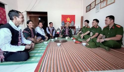 Cán bộ Công an xã Avương vui vẻ trò chuyện với người dân làng Atêếp trong căn nhà “Chiến dịch Quang Trung” của già làng Bling Tươm.