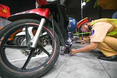 Cán bộ Đội CSGT số 7 soi đèn pin, cẩn thận kiểm tra đối chiếu số khung, số máy của chiếc xe máy vi phạm trước khi tiến hành niêm phong, đưa về bãi tạm giữ.