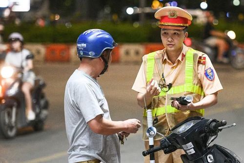 Một nam tài xế chăm chú lắng nghe cán bộ CSGT thông báo lỗi vi phạm và yêu cầu kiểm tra giấy tờ liên quan sau khi xác định có nồng độ cồn.