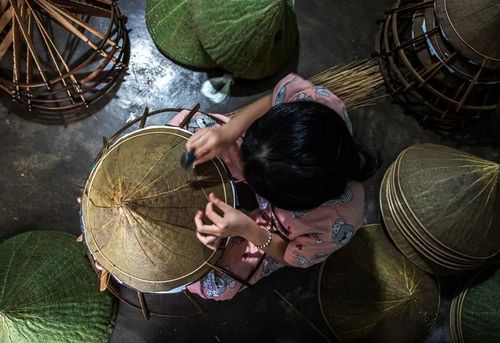 Quy trình làm nón lá sen là sự kết hợp giữa kỹ thuật truyền thống và sự sáng tạo trong xử lý chất liệu mới. (Ảnh: Vân Chi/TTXVN phát)