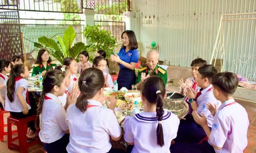 Bữa cơm ấm cúng là dịp để các em học sinh lắng nghe những câu chuyện về một thời khói lửa. Ảnh: Minh Chí