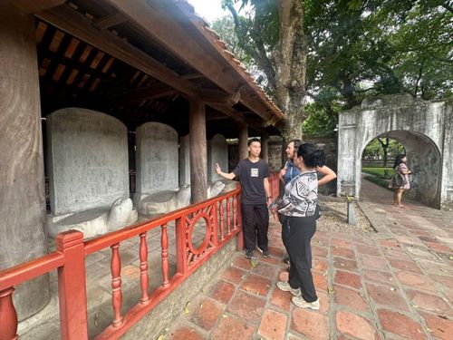 Hai du khách người Mexico chăm chú nghe hướng dẫn viên du lịch giới thiệu về Văn Miếu-Quốc Tử Giám.