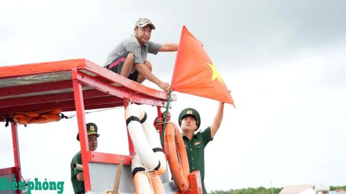 Đồn Biên phòng Đất Mũi hướng dẫn ngư dân treo cờ Tổ quốc trước khi ra khơi. Ảnh: Hoàng Tá