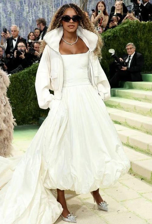 Blue Ivy Carter đã đến dự Met Gala cùng bố mẹ, Beyoncé và Jay-Z, trong lần đầu tiên bước lên bậc thang của Met Gala. Trong lần ra mắt này, cô bé diện một bộ trang phục Balenciaga toàn màu trắng gồm một chiếc váy dạ hội trắng dài đến đầu gối với phần đuôi váy dài thướt tha, kết hợp với một chiếc áo khoác trắng bên ngoài. Ảnh: Getty