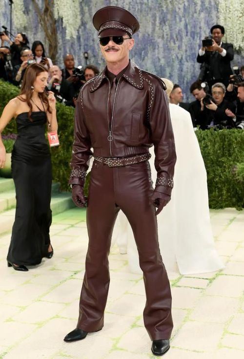 Luke Evans đã bày tỏ lòng kính trọng đối với Tom of Finland bằng bộ trang phục Palomo Spain toàn bằng da với áo khoác, quần và quả địa cầu màu đỏ tía. Chiếc mũ ton sur ton được thiết kế với sự hợp tác của nhà thiết kế mũ người Tây Ban Nha Vivas Carríon. Ảnh: Getty