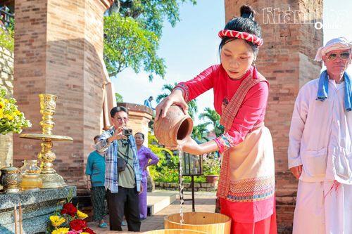 Thiếu nữ Chăm đổ nước từ bình gốm vào thùng.