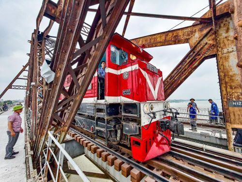 Tàu hỏa lưu thông qua cầu Long Biên trong quá trình thi công, đặt ra yêu cầu kỹ thuật nghiêm ngặt đối với việc đổ bê tông mặt cầu. Ảnh: Trung Nguyên - TTXVN