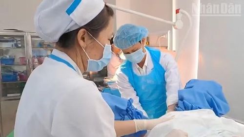 Đội ngũ y bác sĩ thực hiện các thao tác chuyên môn (cắt dây rốn, hỗ trợ sổ nhau, xử trí và khâu tầng sinh môn) cho sản phụ.