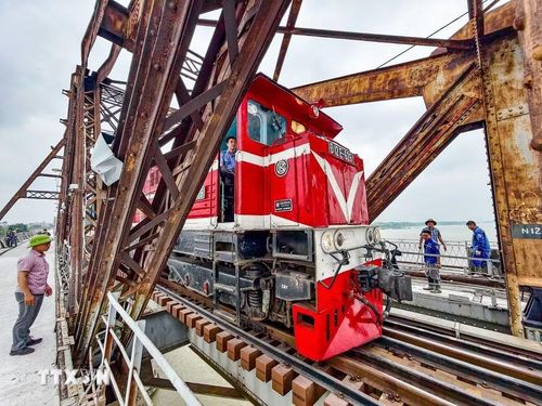 Tàu hỏa lưu thông qua cầu Long Biên trong quá trình thi công, đặt ra yêu cầu kỹ thuật nghiêm ngặt đối với việc đổ bê tông mặt cầu. (Ảnh: Trung Nguyên/TTXVN)