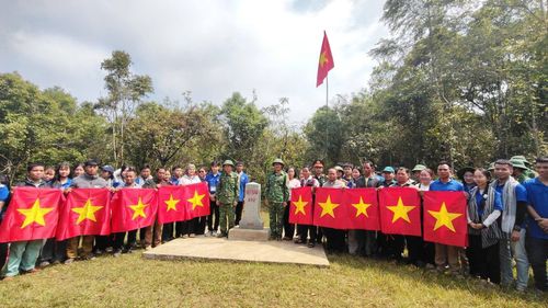 Tặng cờ đỏ sao vàng cho đồng bào Cơ Tu nơi biên giới. Ảnh: SONG THANH