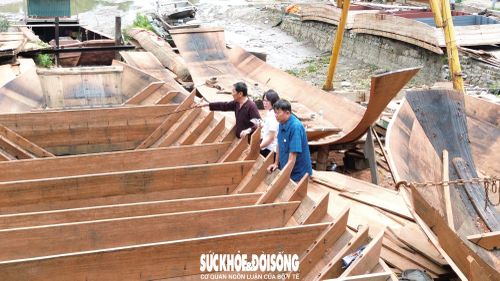 Nghệ nhân Lê Đức Chắn cùng con trai cả kiểm tra từng đường ghép, mối nối của con thuyền tại xưởng đóng thuyền của mình. Ảnh: Tiến Sinh.