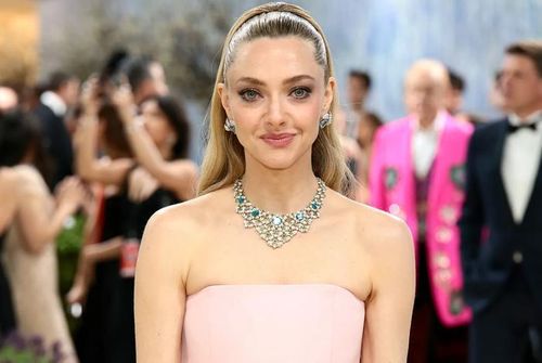 Amanda Seyfried hóa thân như nàng công chúa trong bộ váy Prada màu hồng phấn cùng kiểu tóc búi vương giả đồng điệu. Cô hoàn thiện diện mạo với trang sức Tiffany &amp; Co. gồm khuyên tai kim cương đính aquamarine và vòng cổ nổi bật kết hợp đá xanh zircon, ngọc lục bảo và kim cương. Ảnh: Getty