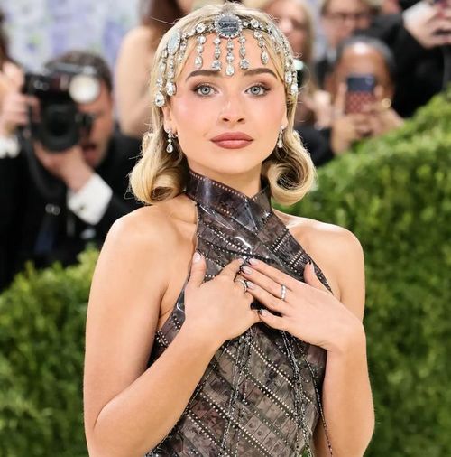 Sabrina Carpenter gây ấn tượng với chiếc váy làm từ các dải phim đính rhinestone, tái hiện những cảnh trong bộ phim Sabrina (1954). Cô còn kết hợp loạt trang sức Chopard, gồm hai dây chuyền kim cương 50 carat, hoa tai 10 carat và phụ kiện đội đầu đính đá lấp lánh. Ảnh: FilmMagic