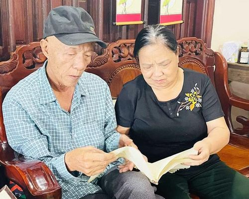 Ông Nguyễn Minh Trí cùng vợ lật giở từng trang nhật ký cha để lại. Ảnh: Phương Dung
