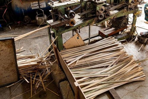 Máy tước vỏ hoạt động liên tục để xử lý những thanh vầu sau khi chẻ đôi. Phần vỏ ngoài được xếp gọn ở bên phải, trong khi thanh vầu mỏng tách ra sẽ rơi từ máy xuống