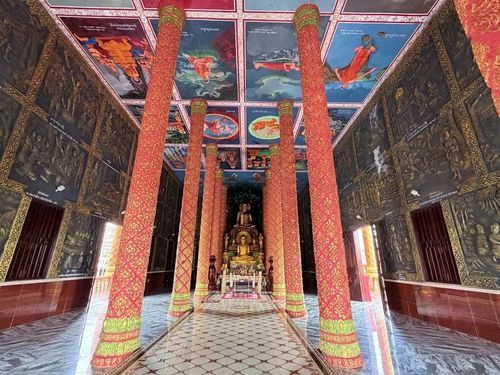 Bên trong chính điện, hai hàng cột lớn vươn cao nâng đỡ mái chùa, tạo không gian rộng thoáng, mát mẻ. Vách, trần chánh điện được phủ kín bằng những phù điêu, bích họa cầu kỳ, rực rỡ sắc màu tái hiện sinh động cuộc đời Đức Phật từ khi đản sinh đến quá trình tu hành đắc đạo. (Ảnh: Thanh Sang/TTXVN)