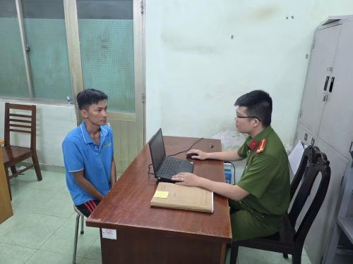 Đối tượng Bùi Trung Quốc (áo xanh trái) tại Cơ quan Cảnh sát điều tra Công an Thành phố Hồ Chí Minh. (Ảnh: CA Thành phố Hồ Chí Minh cung cấp)