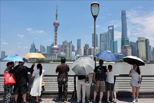 Khách du lịch che ô tránh nắng nóng tại Thượng Hải, Trung Quốc. Ảnh: THX/TTXVN