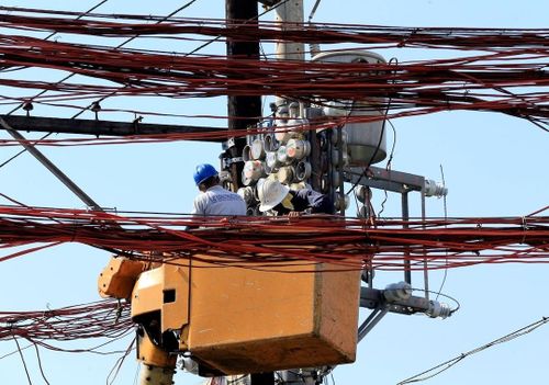 Các công nhân điện lực Philippines sửa chữa công tơ điện ở Manila. Ảnh: Reuters.
