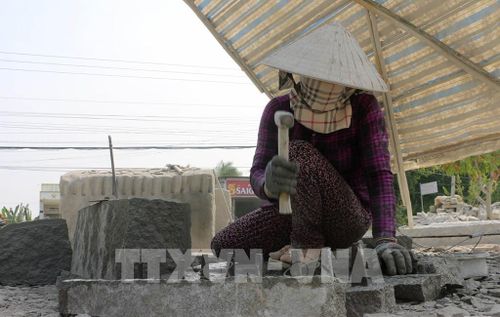 Chị Nguyễn Thị Thi (xã Thoại Sơn, tỉnh An Giang) dùng nêm sắt để chia tách các trụ đá nhỏ từ khối đá. Ảnh: Công Mạo - TTXVN