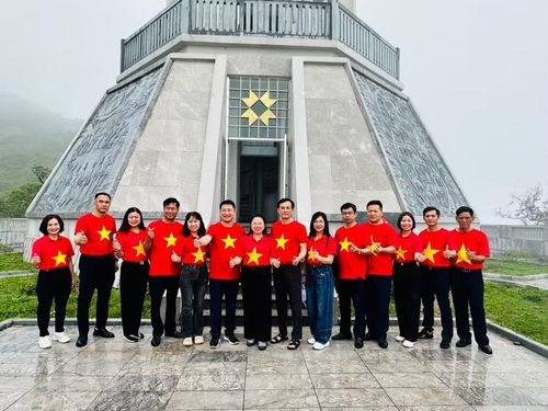 Bà Hoàng Tuyết Ban - Giám đốc Sở GD&ĐT tỉnh Điện Biên (thứ 7 tính từ bên trái) cùng đoàn công tác chụp ảnh lưu niệm dưới chân cột cờ A Pa Chải.