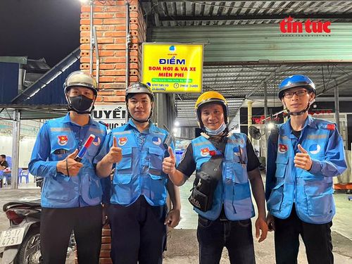 Các thành viên đội SOS Bà Điểm tại một điểm bơm hơi và vá xe miễn phí trên đường Phan Văn Hớn.