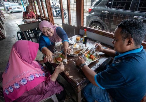 Khách hàng thưởng thức món nasi lemak 50 sen tại quán Warung Lejen ở Selama, Perak. Ảnh: Bernama.