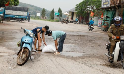  Người dân điều khiển xe máy đánh rơi bao gạo xuống đất vì mặt đường quá xấu. Ảnh chụp sáng 11/5/2026. 
