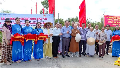 Phó Chủ tịch Ủy ban MTTQ Việt Nam tỉnh Cà Mau Nguyễn Văn Khởi (thứ tám từ trái sang) và đại diện chính quyền địa phương, nhà tài trợ cùng người dân thực hiện nghi thức cắt băng khánh thành cầu Cây Tự (khóm Tân Hóa A, phường Hòa Thành).