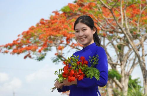 Bạn trẻ chụp ảnh với hàng phượng Lấp Vò. Ảnh: Nhựt An - TTXVN