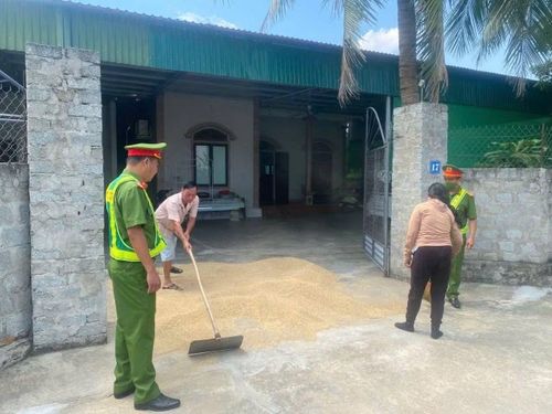 Công an yêu cầu bà Q. gom lúa phơi giữa đường. Ảnh: CACC