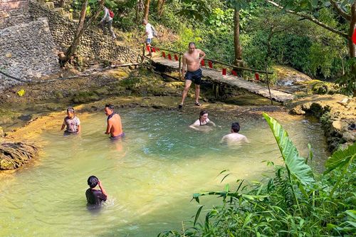 Một số du khách thả mình trong dòng nước mát lạnh dưới bóng cây rừng, tận hưởng không gian yên tĩnh và không khí trong lành.