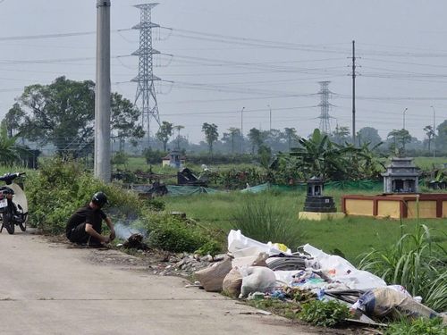 Một người dân ở xã Quốc Oai đốt rác tại một điểm tập kết rác tự phát ven đường. Ảnh: Đức Duy