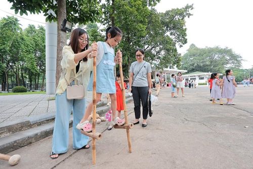 Các em trải nghiệm trò chơi dân gian Đi cà kheo tại Bảo tàng Dân tộc học Việt Nam. Ảnh: Lê Đông