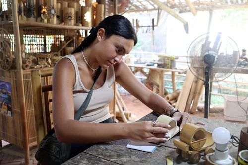 Du khách quốc tế tự tay tạo ra một sản phẩm thủ công bằng chất liệu gỗ tre tại một điểm du lịch thuộc phường Hội An Đông, Đà Nẵng. Ảnh: Đỗ Trưởng – TTXVN
