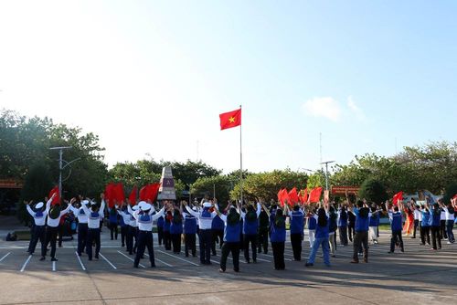 Các thành viên Đoàn công tác số 12 thực hiện màn đồng diễn tại khu vực trước cột mốc đảo Trường Sa, với cờ đỏ sao vàng tung bay phấp phới. Ảnh: Tiến Lực - TTXVN