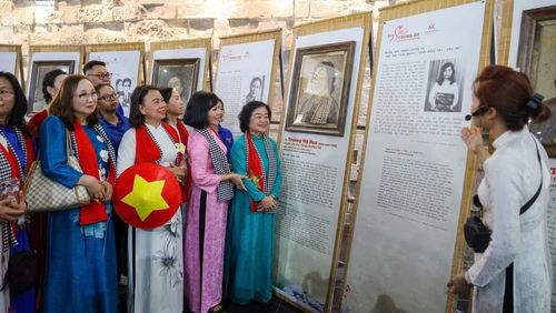 Nguyên Phó chủ tịch nước Trương Mỹ Hoa (áo dài xanh, bên phải) bên tác phẩm chân dung mình được nghệ nhân tạo tác trên lá sen Việt Nam. (Ảnh: Ban tổ chức cung cấp)