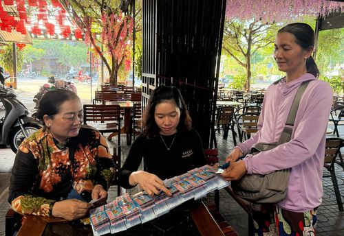 Dù sức khỏe yếu, chị Phan Thị Thúy (bìa phải), ngụ phường Rạch Giá mỗi ngày vẫn rong ruổi bán vé số mưu sinh. Ảnh: CẨM TÚ