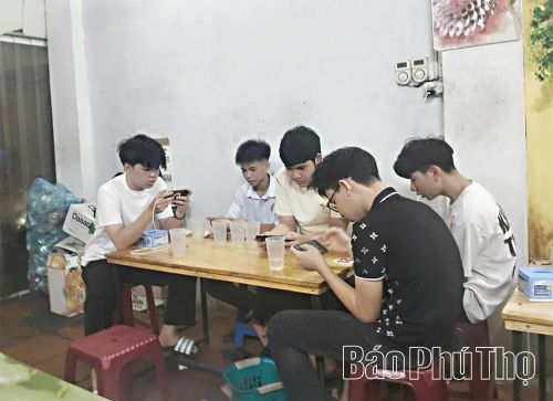 Thanh thiếu niên sử dụng điện thoại chơi game tại hàng quán trong thời gian rảnh.