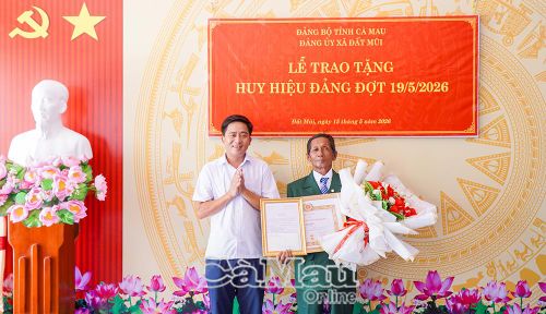 Đồng chí Kiều Minh Tiếng, Bí thư Đảng ủy, Chủ tịch HĐND xã Đất Mũi, trao Huy hiệu 50 năm tuổi Đảng cho đồng chí Hồ Nghị Cho.